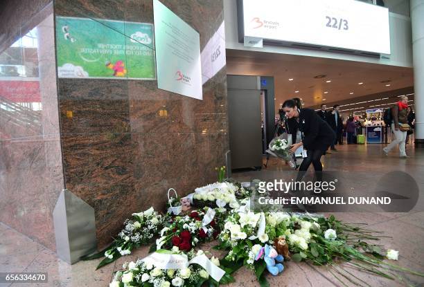 An employee places flowers under a memorial plaque inside a terminal at Brussels' international airport in Zaventem on the first anniversary of the...