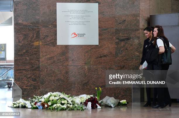 Employees look at flowers placed under a memorial plaque inside a terminal at Brussels' international airport in Zaventem on the first anniversary of...