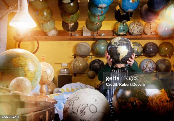 globe maker holding globe in front of face - large group of craftsman stock-fotos und bilder