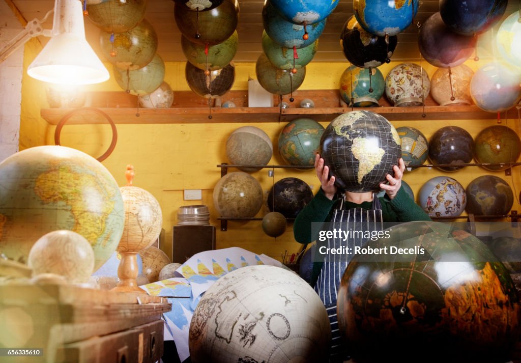 Globe maker holding globe in front of face