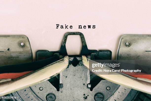 fake news type on vintage typewriter - newspaper article stockfoto's en -beelden