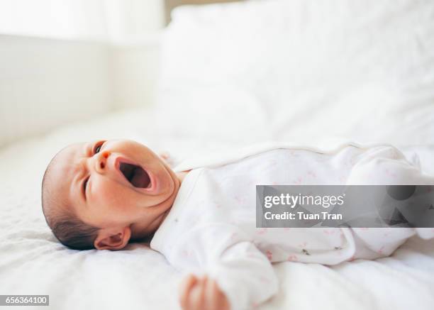 baby girl yawning on bed - sleeping baby stock pictures, royalty-free photos & images