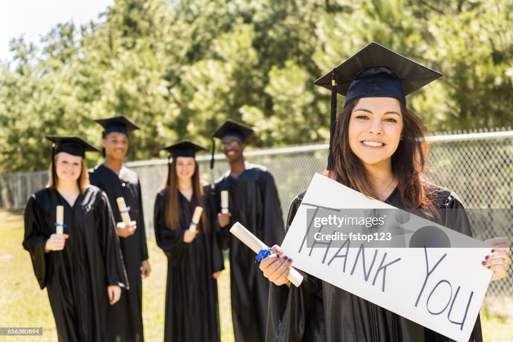 Latin descent college, high school student holds "Thanks, Dad" sign at graduation.