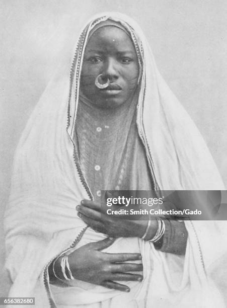 Women wearing traditional native dress, including a veil and nose ring, Sudan, 1922. .