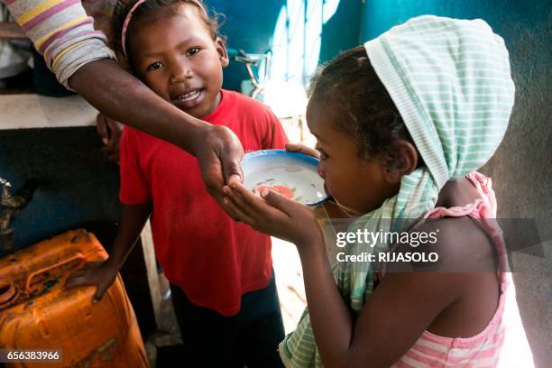 Young girl drinks water from a bowl at a public fountain during a period when the public water supply has been cut off, in the Isotry district of...