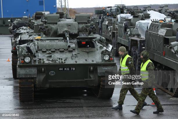 Estonian soldiers walk past British Army Warrior tanks and other armoured vehicles of the 5th Battalion The Rifles after the vehicles arrived by ship...