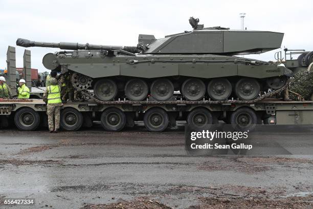 Crew secures a British Army Challenger 2 tank of the 5th Battalion The Rifles to a truck trailer after the tank and other heavy vehicles arrived by...