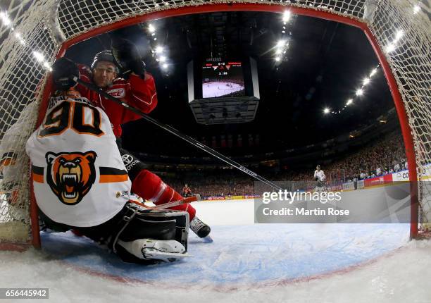 Alexander Sulzer of Koeln slides into Felix Brueckmann, goaltender of Wolfsburg during the DEL Playoffs quarter finals Game 7 between Koelner Haie...