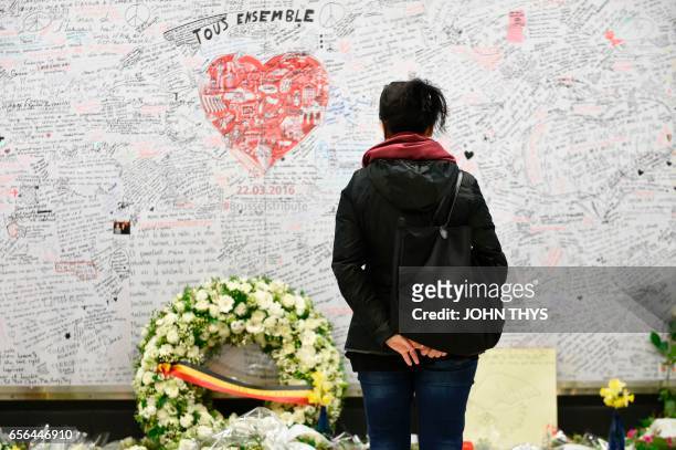 Woman stands in front of a remembrance wall on March 22, 2017 at the Maelbeek - Maalbeek subway station in Brussels, during the commemorations...