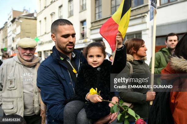 Child carries flowers and a Belgian flag during a commemorative march as Belgium marks the first anniversary of the twin Brussels attacks by Islamic...