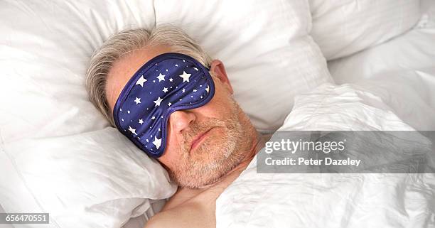 mature man sleeping wearing eye mask close up - senior im bett stock-fotos und bilder