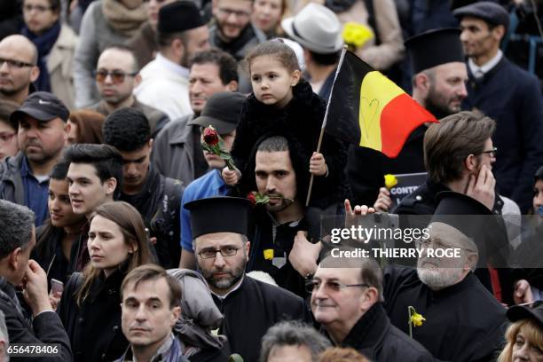 Child carries a flower and the Belgian flag following a commemorative march at La Bourse in Brussels on March 22, 2017 as Belgium marks the first...