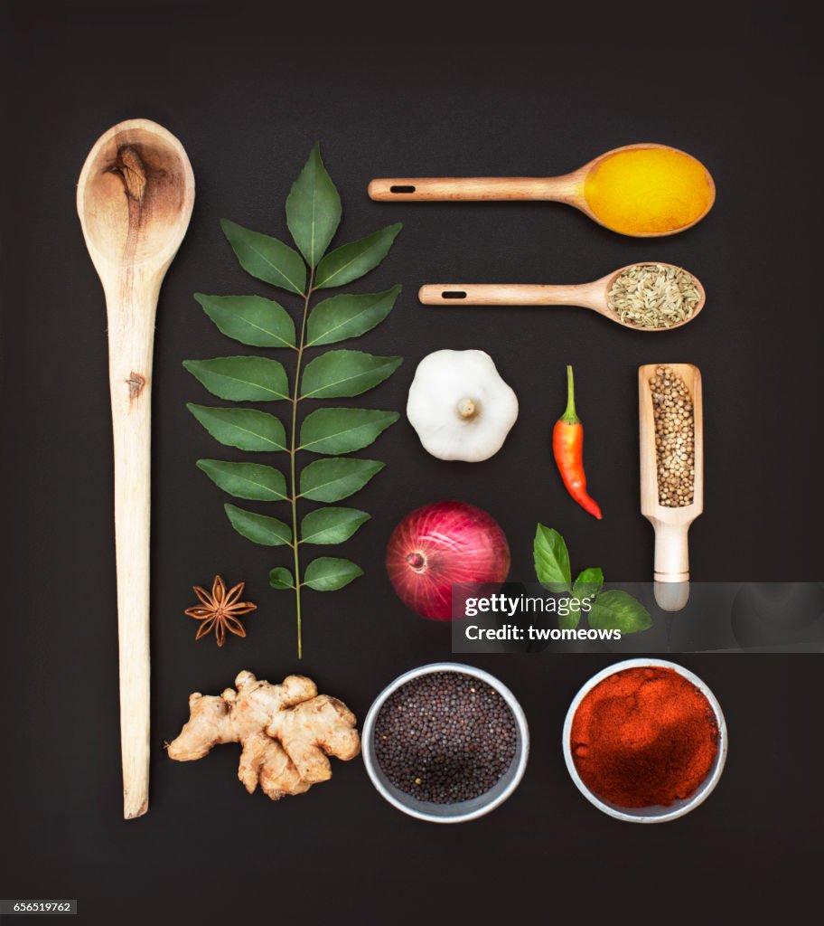 Assorted herbs and spices on black background.