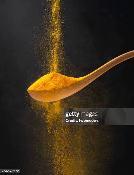 close up view of turmeric powder in wooden spoon. - poder stock pictures, royalty-free photos & images