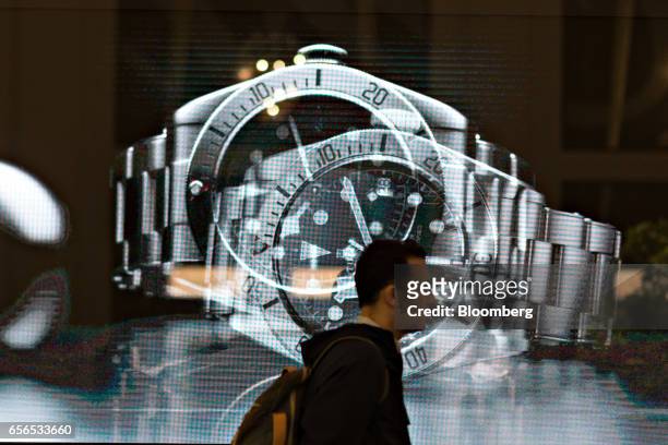 Visitor walks past a digital screen displaying luxury wristwatches during the 2017 Baselworld luxury watch and jewellery fair in Basel, Switzerland,...