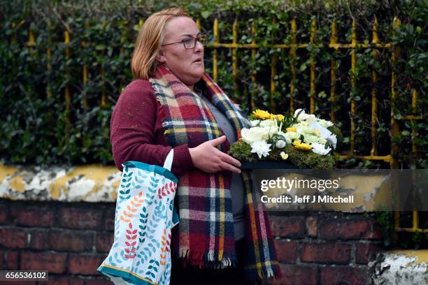 Flowers are carried by a woman as mourners pay ther respects at the home of Martin McGuinness on March 22, 2017 in Londonderry, Northern Ireland....