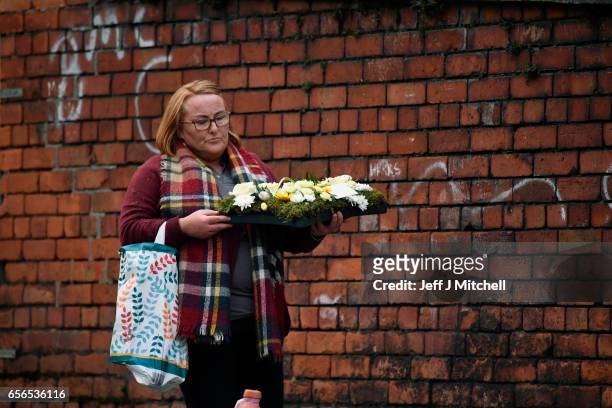 Flowers are carried by a woman as mourners pay ther respects at the home of Martin McGuinness on March 22, 2017 in Londonderry, Northern Ireland....