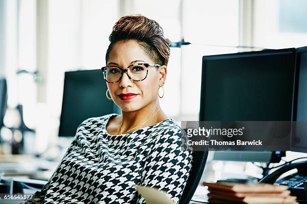 smiling businesswoman seated at office workstation - business woman blouse stock-fotos und bilder