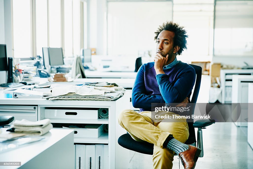 Businessman with hand on chin seated in office