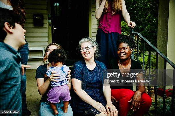 lesbian couple sitting on front porch with family - leaninlgbt stock pictures, royalty-free photos & images