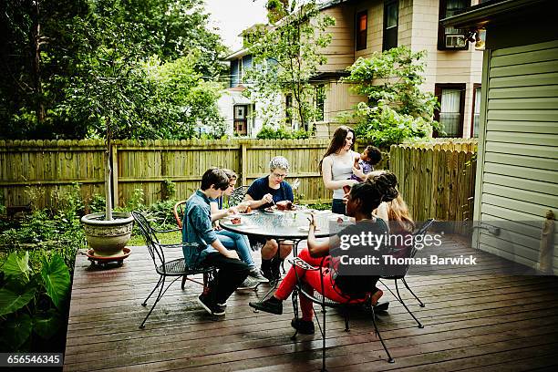 family eating birthday cake together on patio - family with five children stock pictures, royalty-free photos & images