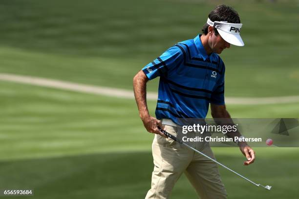 Bubba Watson picks up a ball with his club after putting on the 16th hole of his match during round one of the World Golf Championships-Dell...