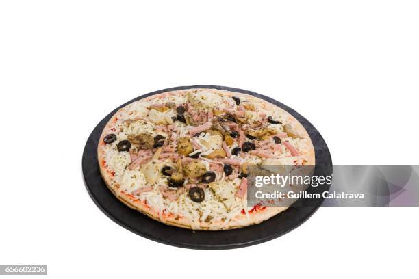pizza ready to put in the oven on black plate and white background - jamón stockfoto's en -beelden