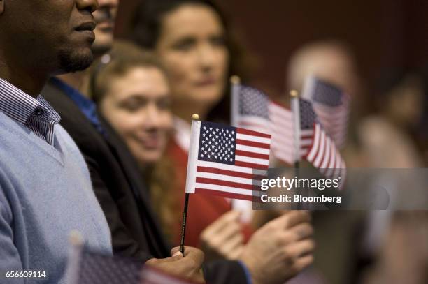 People hold miniature American flags during a naturalization ceremony in San Diego, California, U.S., on Wednesday, March 22, 2017. Hawaii's attorney...