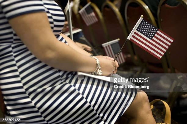Woman holds a miniature American flag during a naturalization ceremony in San Diego, California, U.S., on Wednesday, March 22, 2017. Hawaii's...