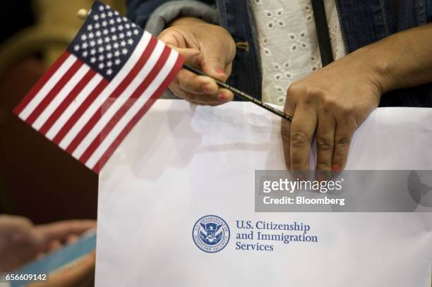 Woman holds a miniature American flag and her papers during a naturalization ceremony in San Diego, California, U.S., on Wednesday, March 22, 2017....