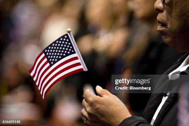 Man holds a miniature American flag during a naturalization ceremony in San Diego, California, U.S., on Wednesday, March 22, 2017. Hawaii's attorney...