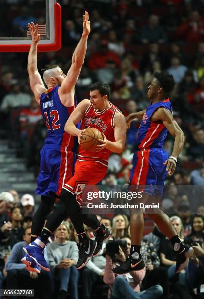 Paul Zipser of the Chicago Bulls leaps to pass between Aron Baynes and Stanley Johnson of the Detroit Pistons at the United Center on March 22, 2017...