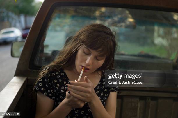 women lighting a cigarette on the back of her pick up truck - beautiful women smoking cigarettes 個照片及圖片檔