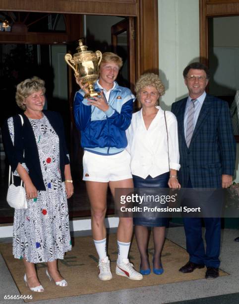 Boris Becker of West Germany holds the trophy surrounded by his family after defeating Ivan Lendl of Czechoslovakia on Centre Court during the men's...