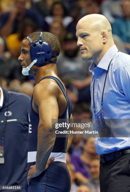 Head coach Cael Sanderson of the Penn State Nittany Lions stands on the mat with Mark Hall during the championship finals of the NCAA Wrestling...