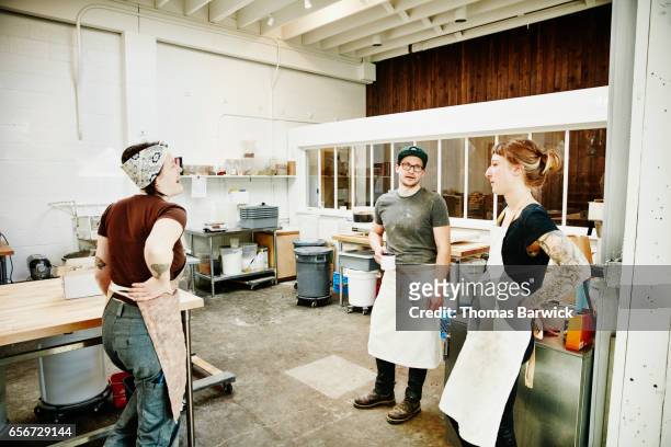 group of bakers in discussion while taking a break during morning production - bäckerin stock-fotos und bilder