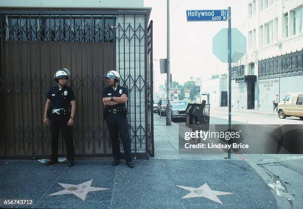 Rodney King Riot. Two LAPD officers in riot helmets standing guard on Hollywood Boulevard's Walk of Fame the morning after fires and looting reached...