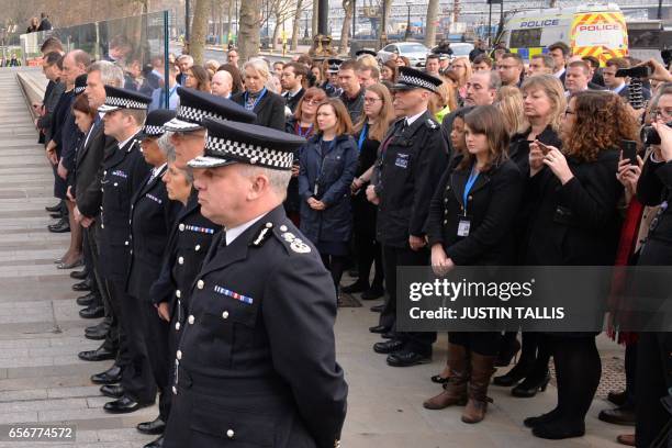 Police officers and staff pause outside the headquarters of the Metropolitan Police Service at New Scotland Yard in central London on March 23, 2017...