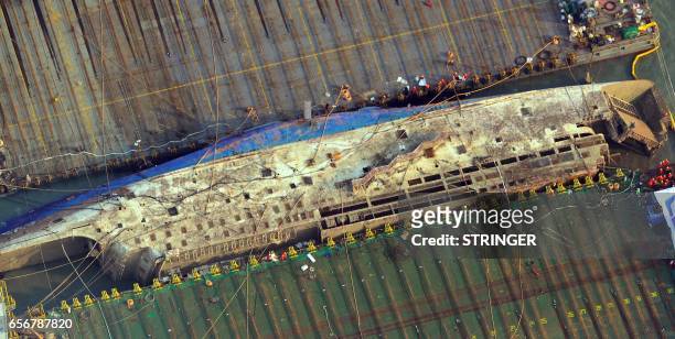 This aerial image shows part of the damaged Sewol ferry between two barges after being raised during a salvage operation at sea off the southwestern...