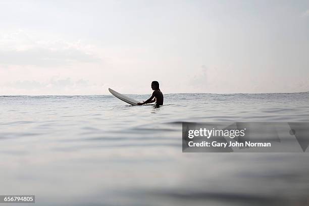 young surfer relaxing on surfboard in the ocean - surf stockfoto's en -beelden