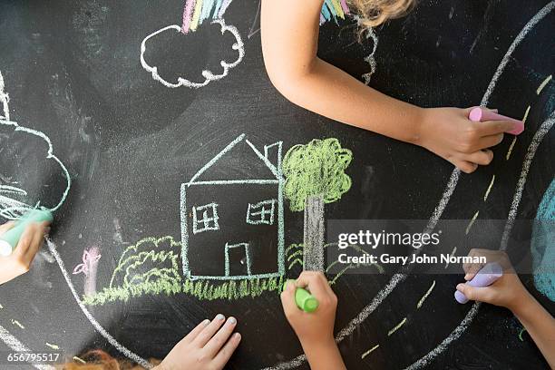 young hands drawing home scene on chalk board - family drawing stock-fotos und bilder