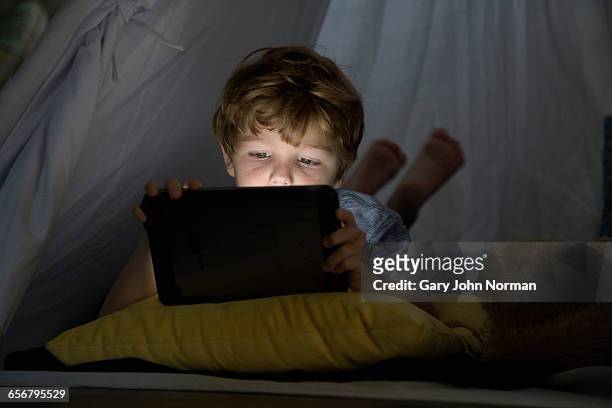young boy's face lit by digital tablet screen - children on a tablet stockfoto's en -beelden