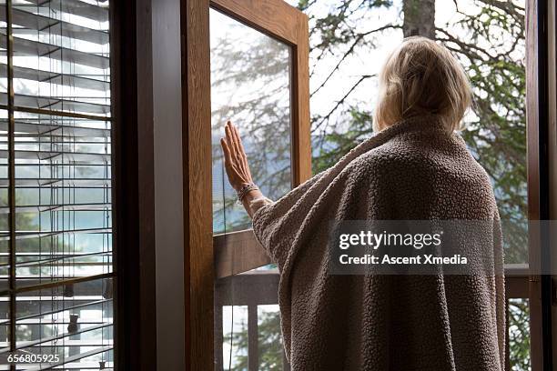 woman pushes door ajar to look out to lake - lüften stock-fotos und bilder