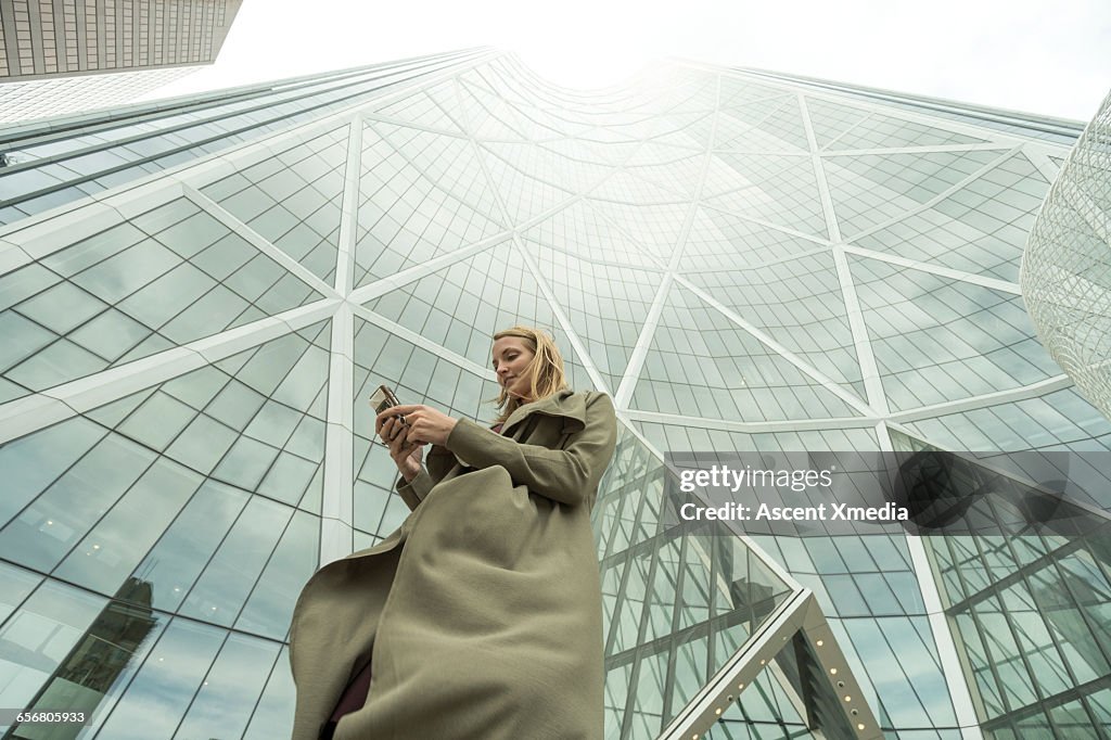 Woman sends text on smart phone, city center