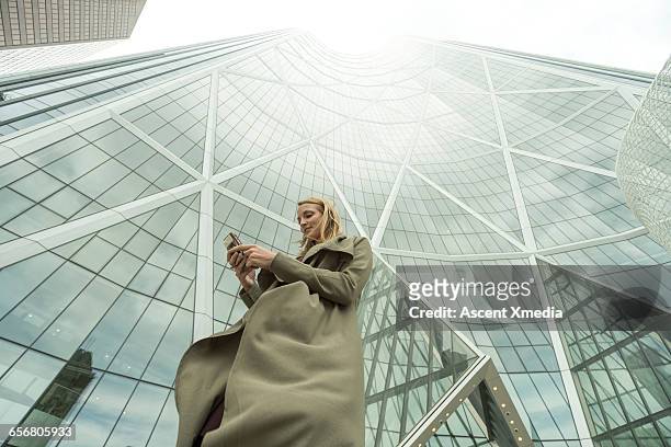 woman sends text on smart phone, city center - low angle view stock pictures, royalty-free photos & images
