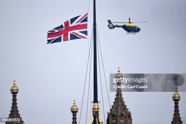 Police helicopter hovers near a Union Flag flying at half mast from the Houses of Parliament following yesterday's attack, on March 23, 2017 in...