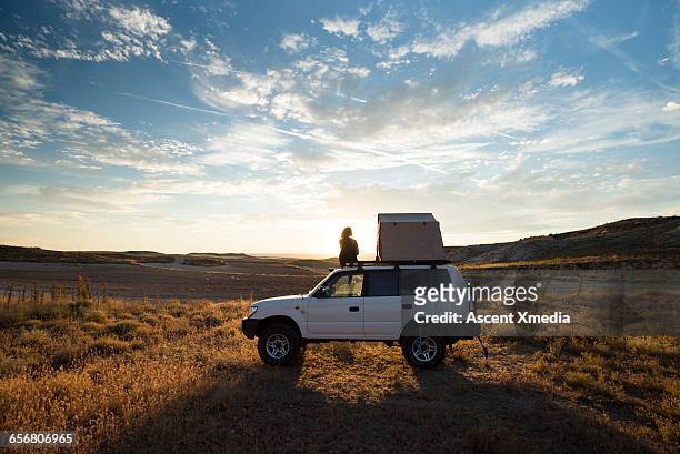 woman looks out from top of vehicle with tent - road trip stock pictures, royalty-free photos & images