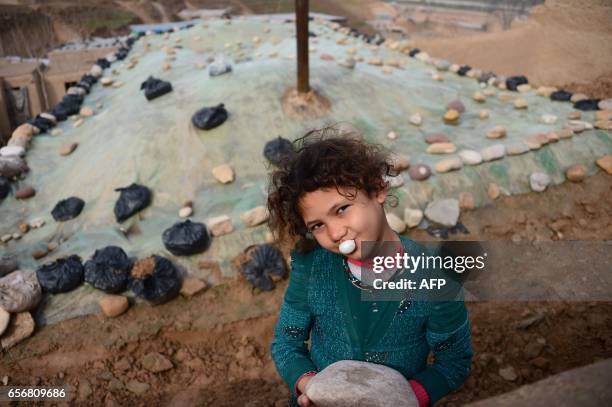 An Afghan girl blows a chewing gum bubble as she poses for a photograph in Badghis province on March 23, 2017. / AFP PHOTO / HOSHANG HASHIMI