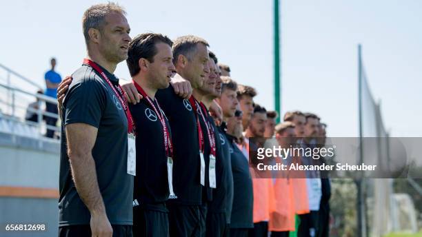 Head coach Christian Wueck of Germany and the assistant team of Germany sing the national anthem during the UEFA U17 elite round match between...