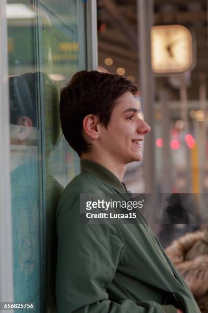 warten auf öffentliche verkehrsmittel - junger mann allein photos et images de collection